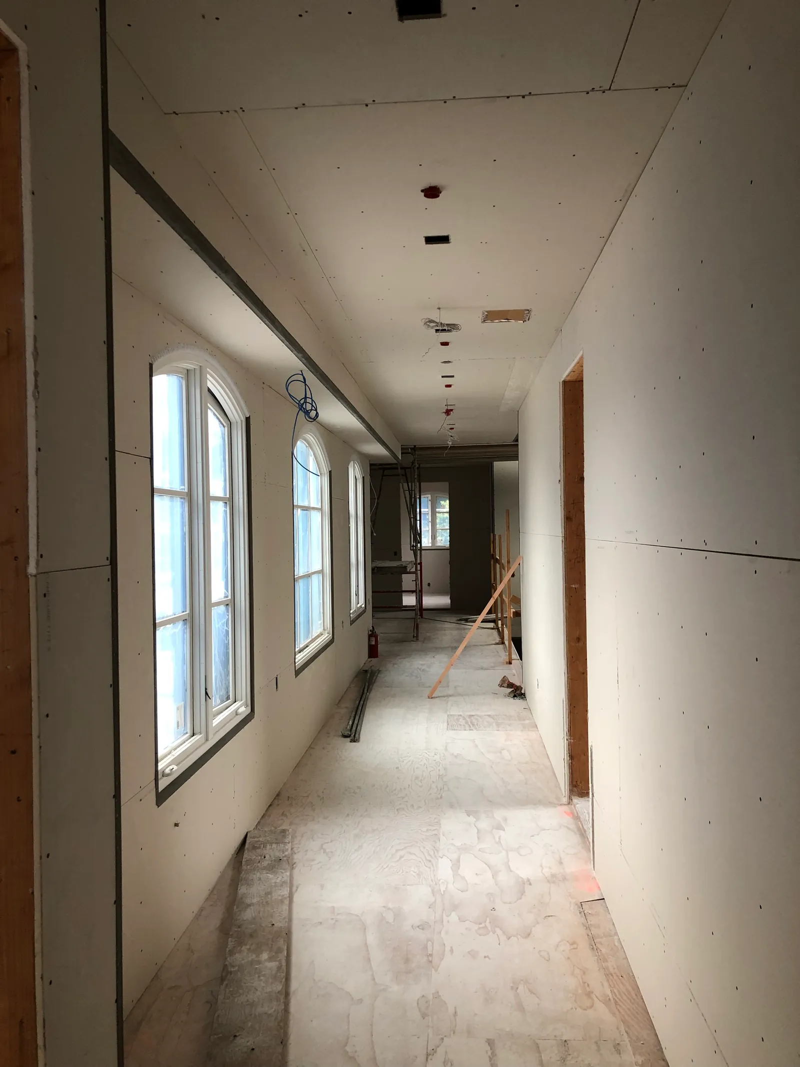 Long gallery corridor with drywall hung around exposed timber